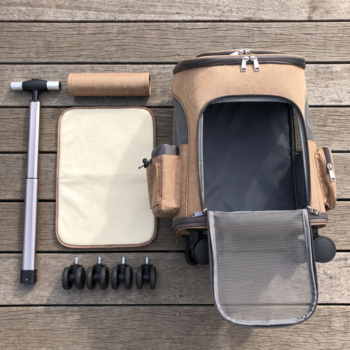 Top-down flat lay of the Apollochi tan wheeled cat carrier opened out with its fleece base mat and rolled top pad on an Australian timber deck